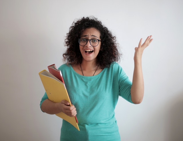 Woman holding folders surprised she almost is done creating a homeschool plan