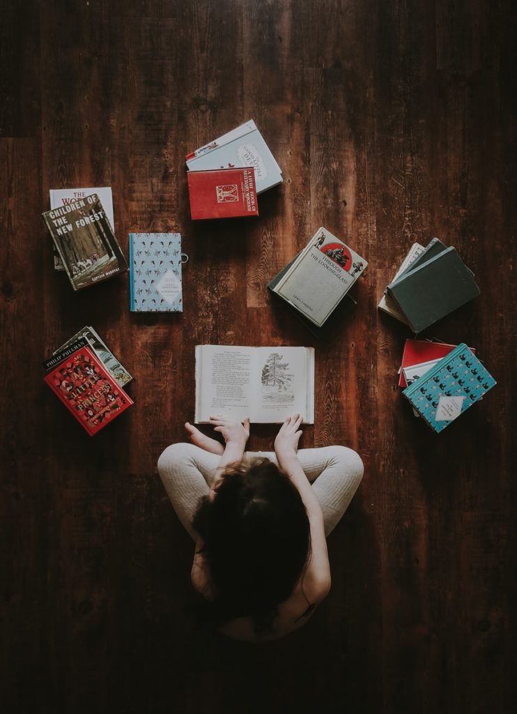 Girl looking at books on the floor from her homeschool booklist