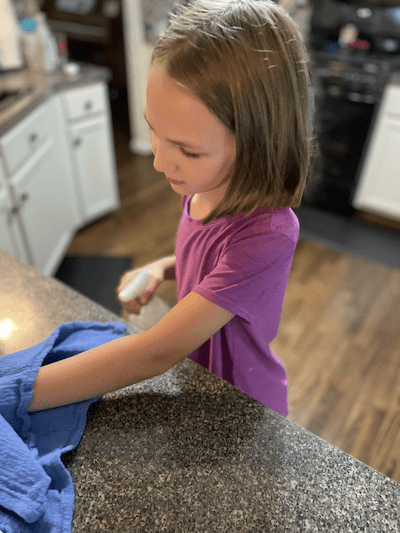 young homeschooled girl cleaning the counter and managing housework