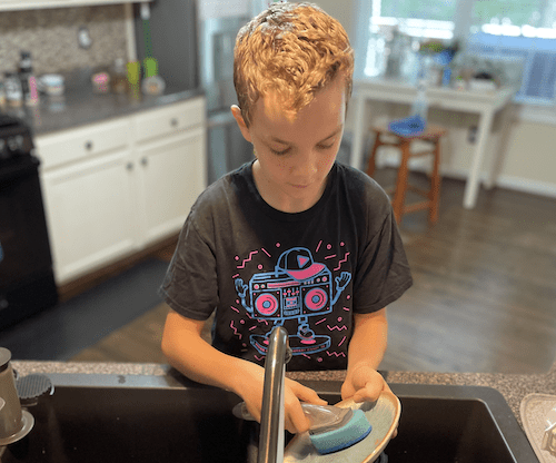 young homeschooler cleaning dishes
