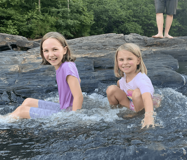two smiling girls sitting in the water