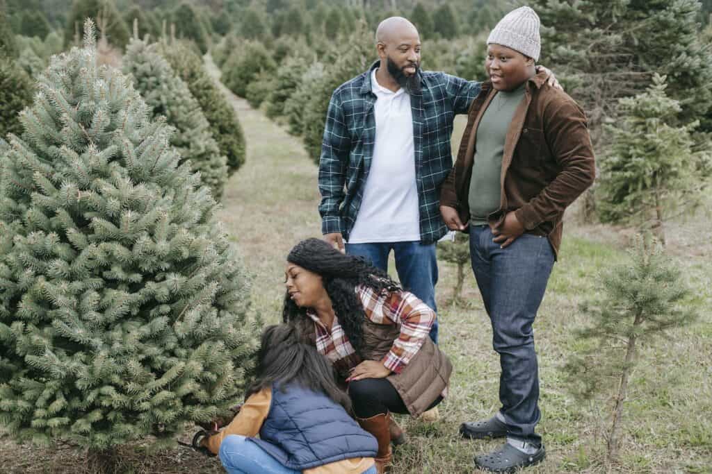 Family cutting down a christmas tree for holiday traditions