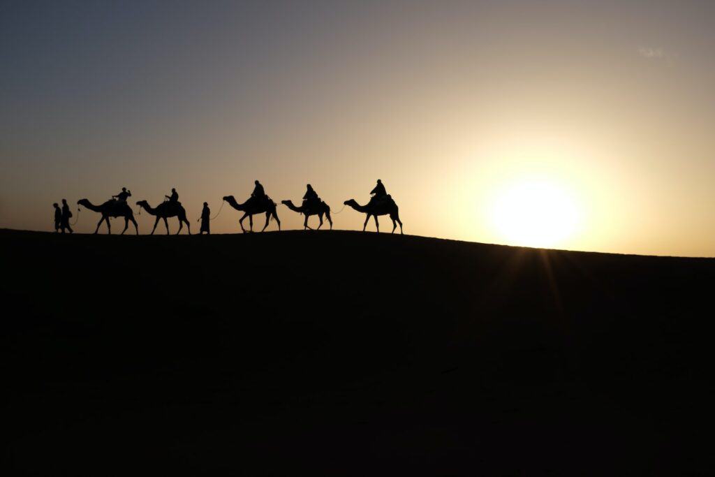 silhouette of people riding on camels reminds of wise men holiday traditions