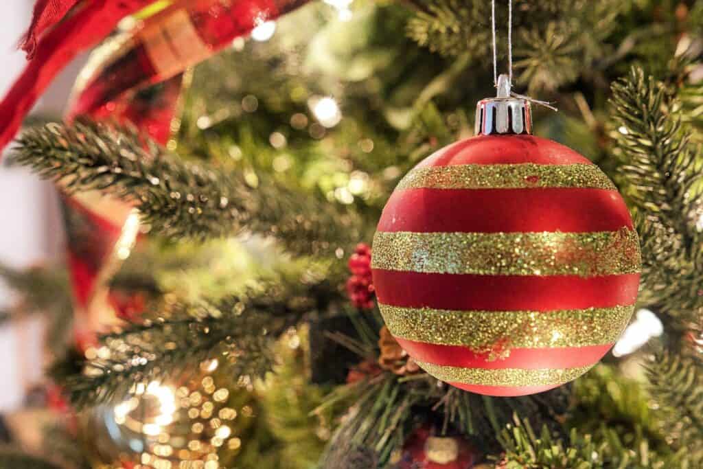 red and white ornament hanging on green christmas tree. holiday traditions