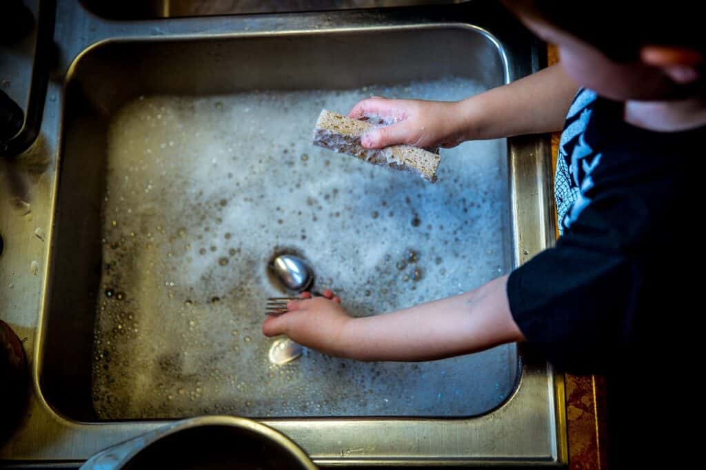 child washing dishes, soap, sink, helping with household chores