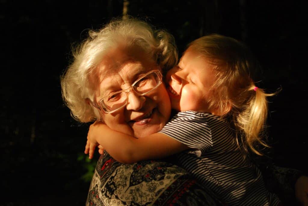 old woman in black and white striped shirt hugging girl in black and white striped shirt