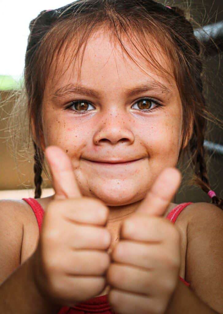 girl in pink tank top with thumbs up. Positive attitude