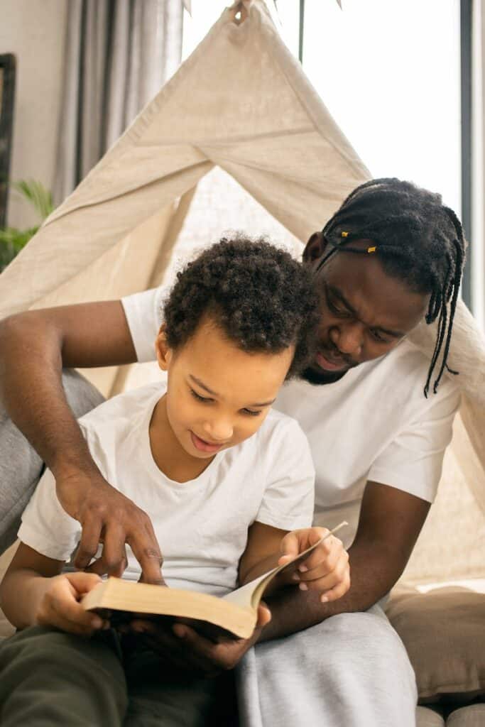 Happy father and little son smiling and reading book together