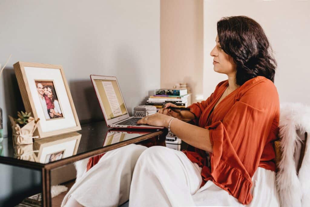 woman in orange shirt using laptop computer to look at homeschooling websites