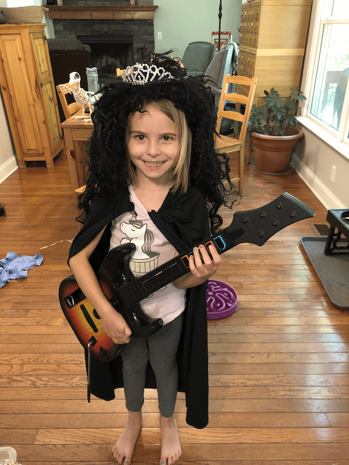 kindergarten homeschool girl having fun in a costume with a play guitar