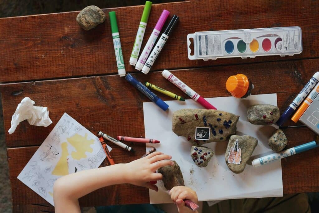 child holding stone and coloring with markers in his homeschool curriculum