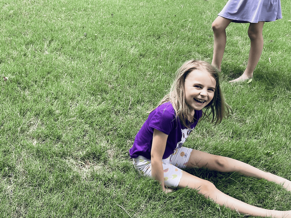 a young girl laughing in the grass
