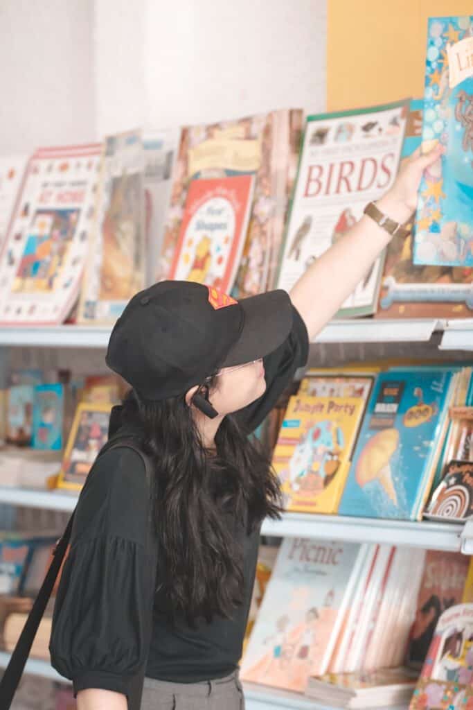 woman holding book on a shelf, shopping for homeschool curriculum