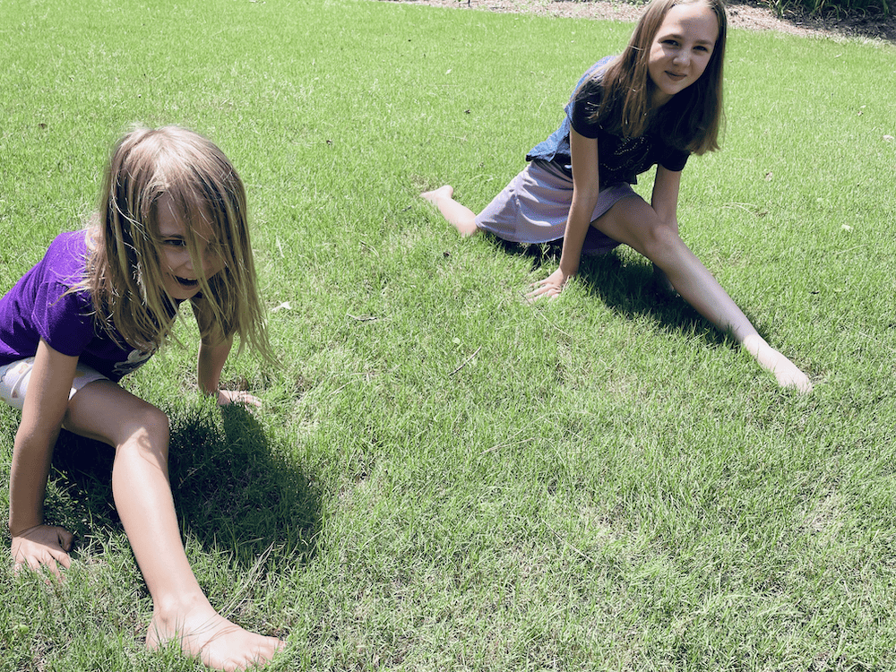 2 girls doing the splits in the grass