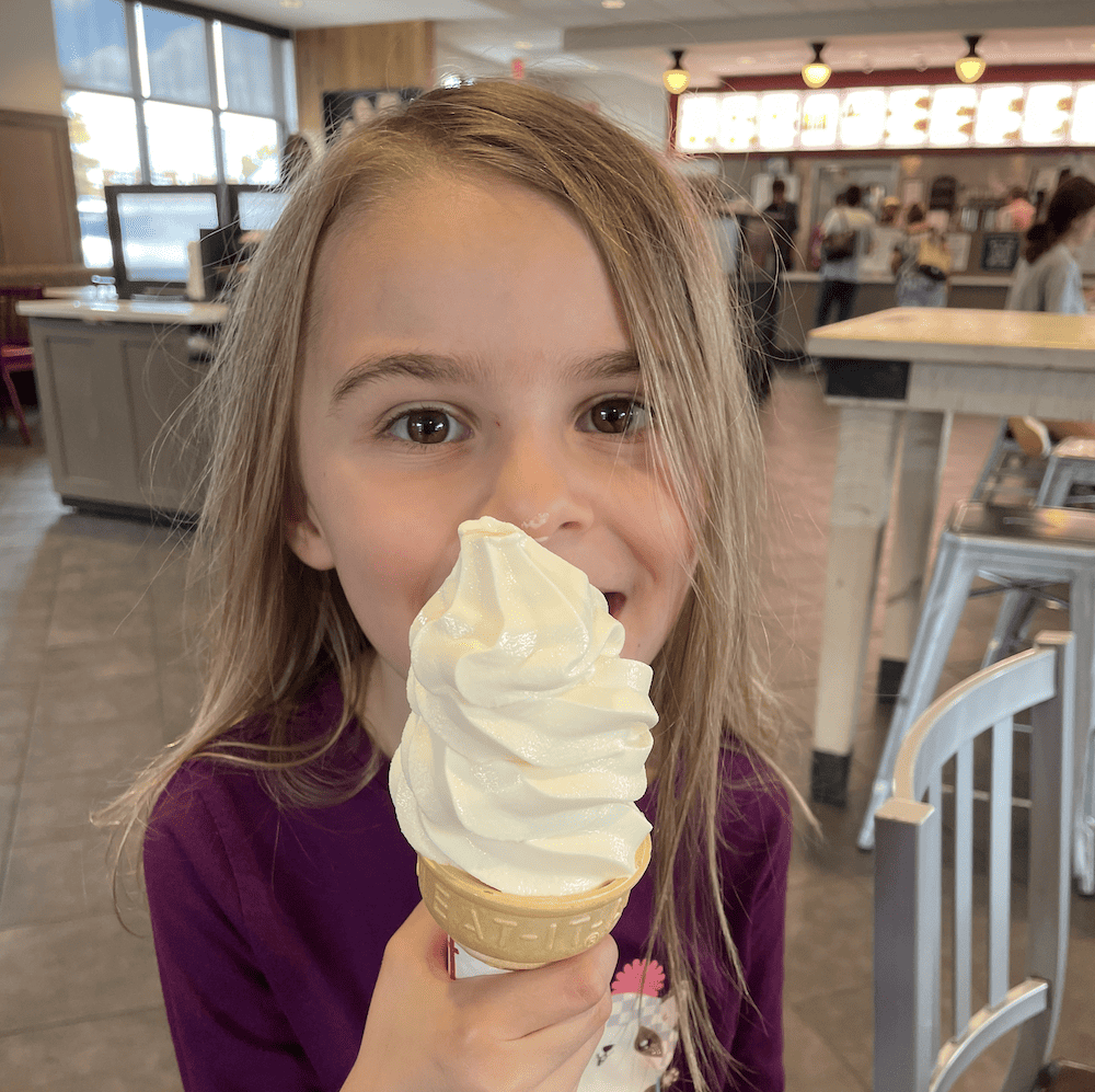 a little girl eating a big ice cream cone