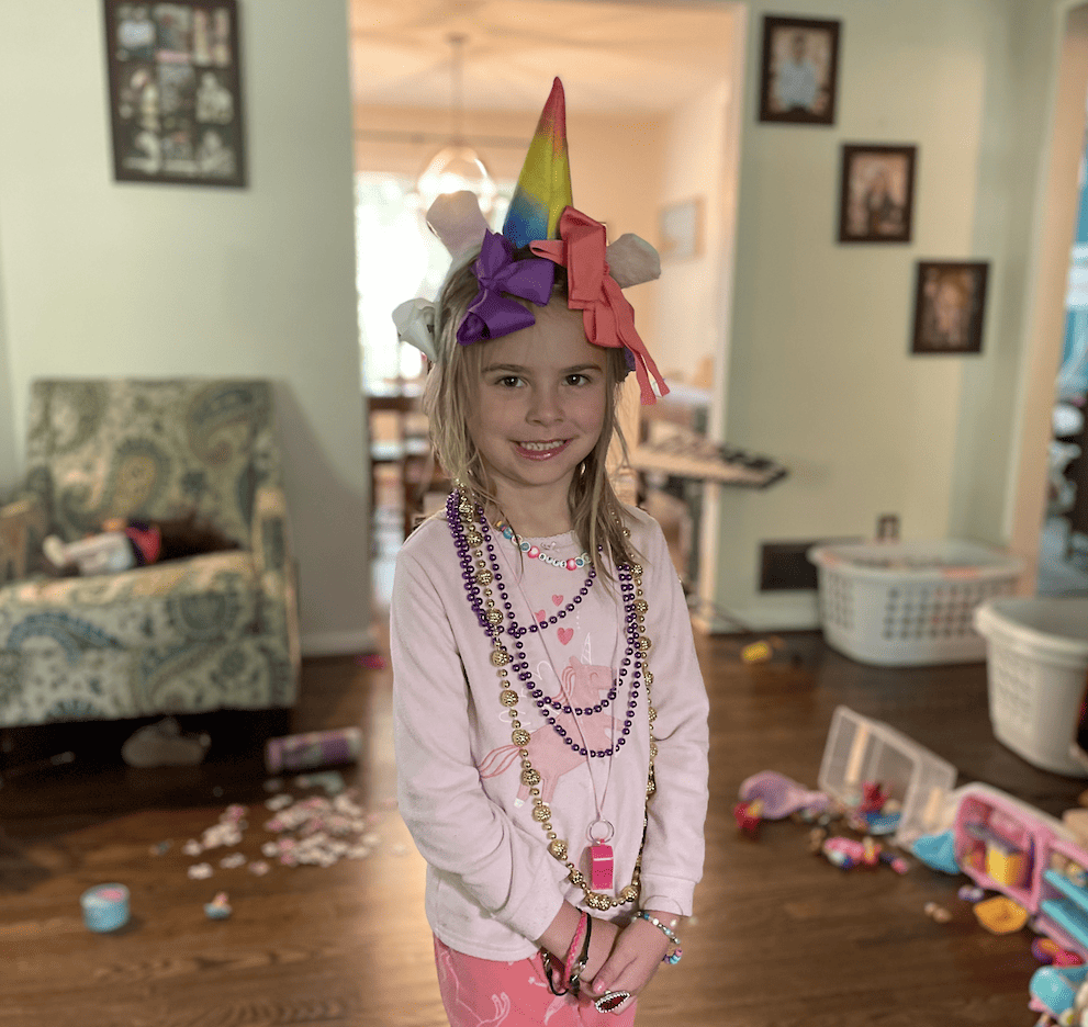 a little girl smiling with lots of bows in her hair and lots of plastic necklaces around her neck