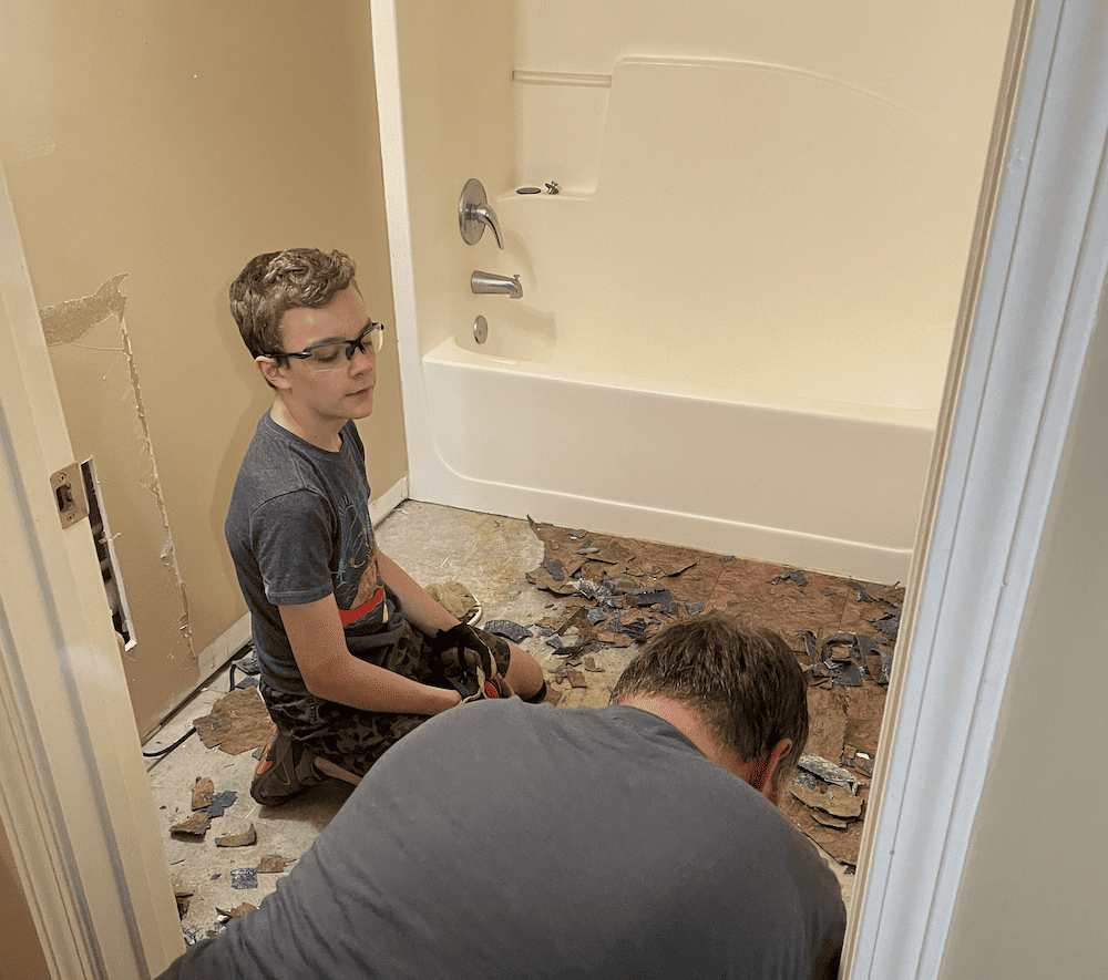 a young boy helping his dad work on flooring