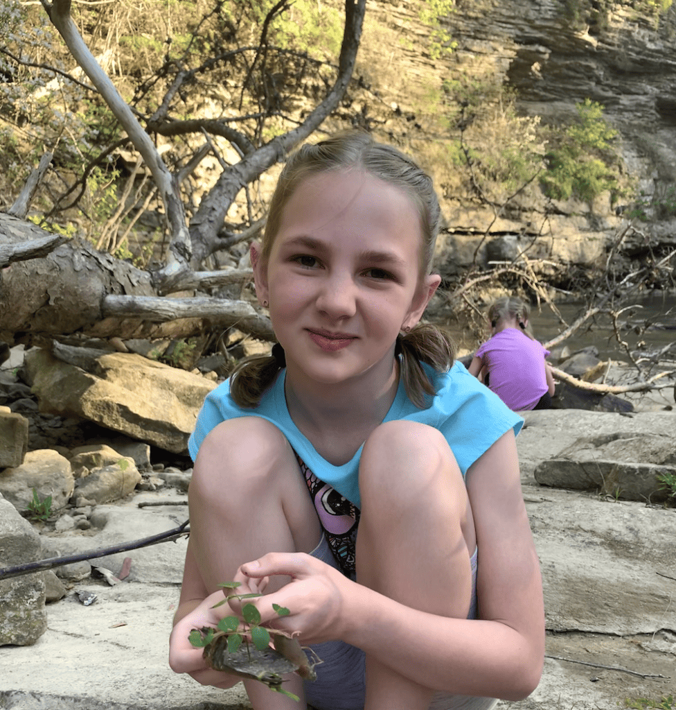 a young girl smiling by a creek