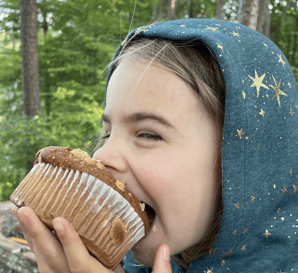 young girl eating a big muffin
