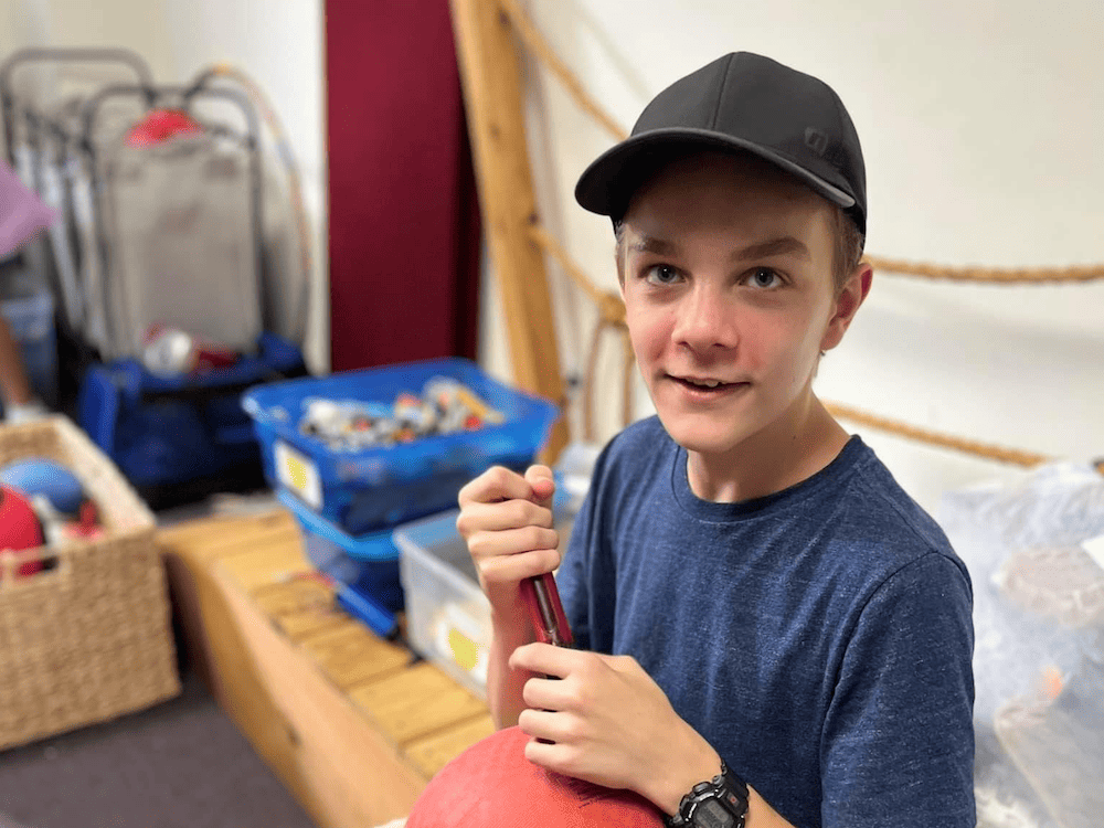 boy in hat blowing up a ball