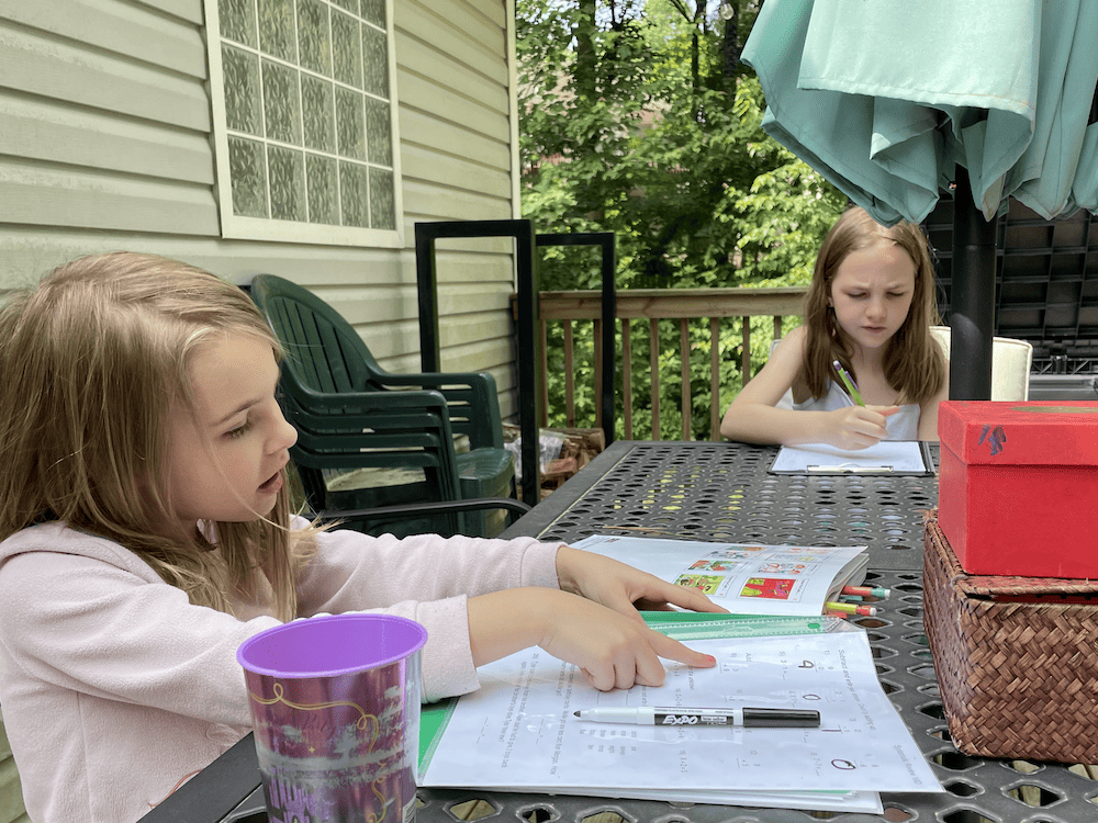 two girls doing school outside