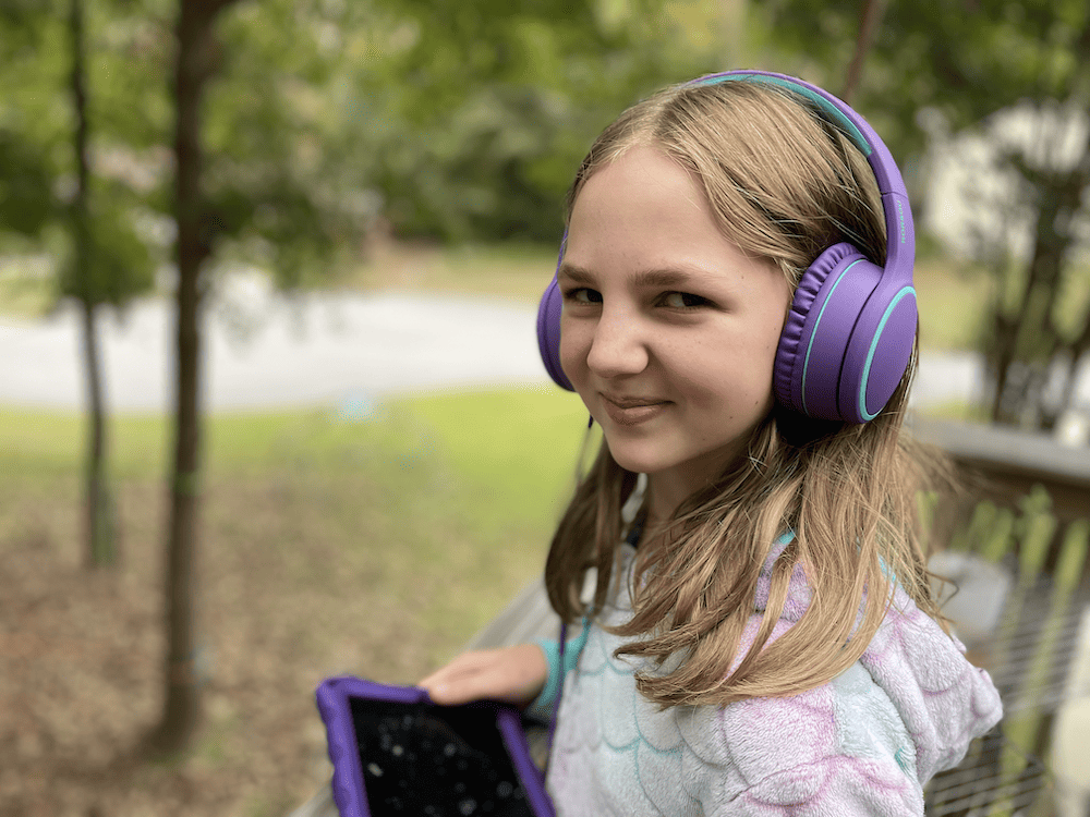 girl with purple headphones on, listening to an audiobook