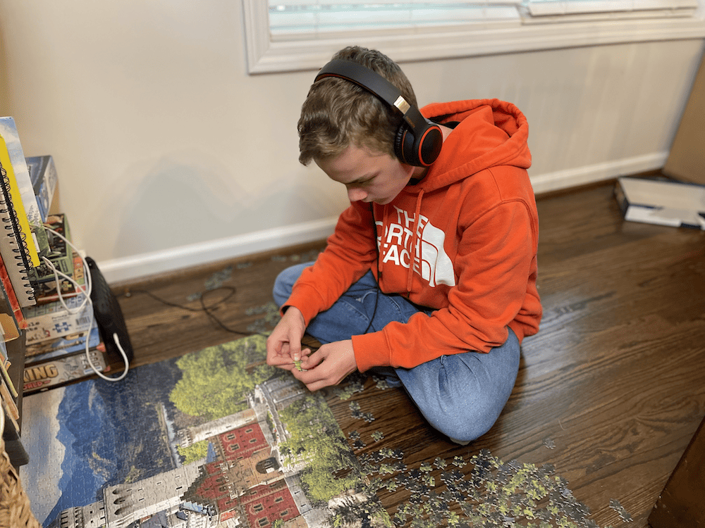 boy in orange sweatshirt doing a puzzle with headphones on