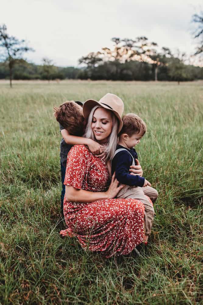 woman and two children on grass field